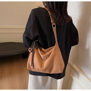 Brown suede hobo tote bag with chocolate charm and woven tassel details on side