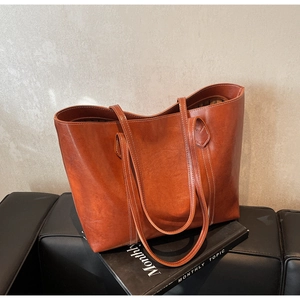 Detail of retro brown leather tote bag with white contrast stitching on a black sofa