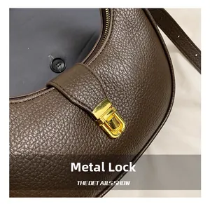 Detailed close-up of premium gold hardware lock on dark brown pebble leather handbag