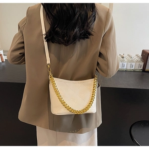 Detail der weißen gesteppten Eimertasche mit Goldkette an weiblichem Modell