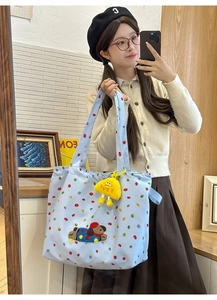 Detail of light blue canvas tote with cartoon dog embroidery and plush charm pendant
