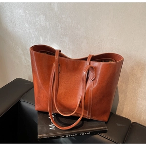 Close-up of caramel leather tote bag with vintage texture and white stitching details