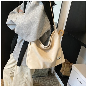Detail view of large cream leather tote bag featuring a decorative silver metal buckle