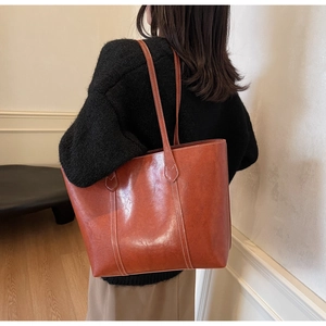 Brown leather tote bag with contrast stitching shown in a stylish lifestyle setting