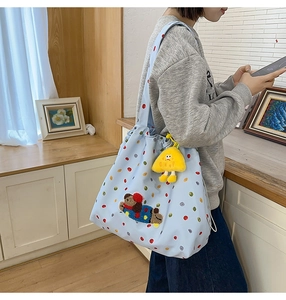 Detail of light blue polka dot tote bag with bear patch and yellow monster charm