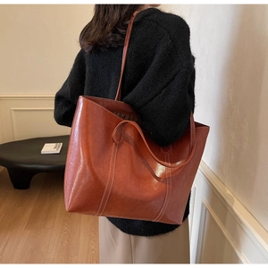 Detail view of large brown vintage tote bag featuring contrast white stitching and leather texture