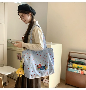Detail of light blue polka dot tote bag featuring a cute plush puppy patch and yellow charm