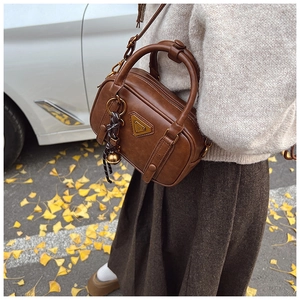 Detail der vintage dunkelbraunen Boston-Tasche mit Metalllogo und gewebtem Anhänger