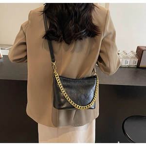 Detail der schwarzen Stepptasche mit goldener Kette auf der Modellschulter