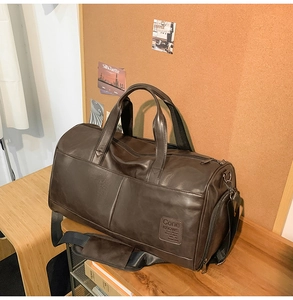 Close-up of the vintage brown PU leather duffel bag featuring an embossed brand logo