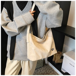 Detail view of cream leather tote bag with vertical stitching and wide strap