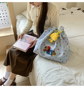 Detail of light blue drawstring tote bag with colorful dots and bear embroidery