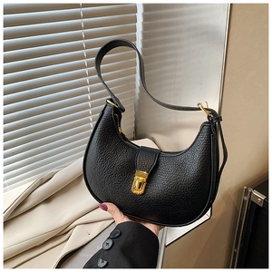 Detail view of black lychee grain leather texture and gold buckle on hobo bag