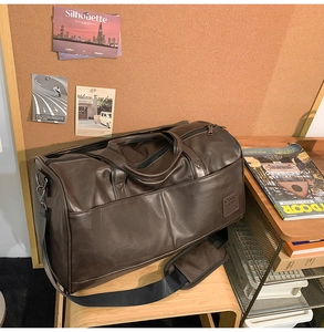 Macro detail of vintage brown leather travel bag featuring a branded logo and front pocket