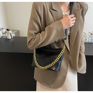 Detail der schwarzen gesteppten Beuteltasche mit eleganter goldener Kette und Gurt