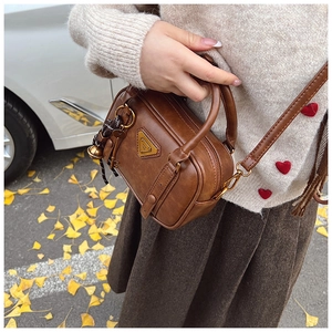 Detail of vintage brown leather handbag with gold triangle plate and charms in autumn setting