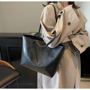 Detail of high-capacity black tote bag featuring distinctive white contrast stitching