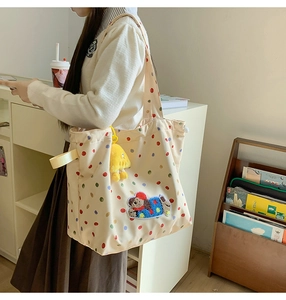 Detail of canvas tote bag with colorful polka dots, dog patch, and yellow plush charm