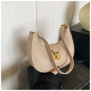 Detail of beige crescent bag featuring lychee grain leather and golden hardware