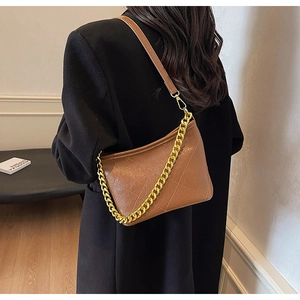 Braune gesteppte Beuteltasche mit Goldkette am Modell in Innenräumen präsentiert