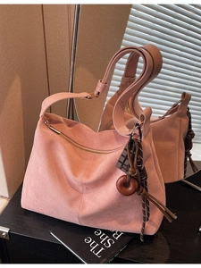 Pink suede hobo tote bag with wide shoulder strap and charm detail for daily commute