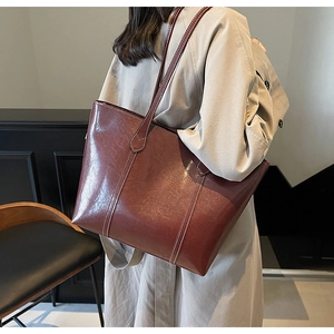 Detail of burgundy tote bag showing premium oil wax leather and white contrast stitching