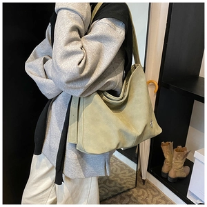 Detailed side view of a large sage green suede tote bag worn on a shoulder for daily use