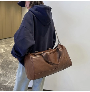 Detailed view of deep brown cylinder travel bag worn by a model in casual setting