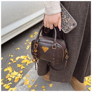 Detail view of vintage dark brown handbag featuring golden hardware and decorative key charm