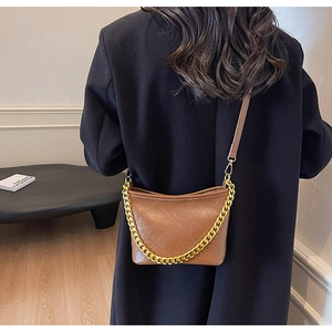 Detail einer braunen gesteppten Beuteltasche mit goldener Kette und Leder-Schultergurt