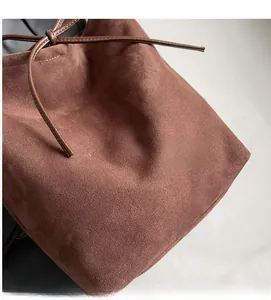 Detail showing soft brown suede texture and bow drawstring on vintage bucket bag
