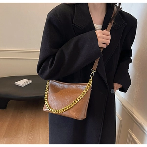 Makroansicht der braunen gesteppten Umhängetasche mit goldener Kette und glänzendem Leder