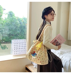 Detailed view of cream canvas tote bag with colorful dots and a cute puppy patch