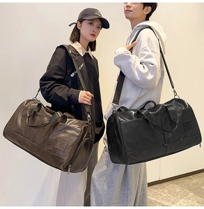 Detail view of large vintage leather travel bags in black and brown with shoulder straps