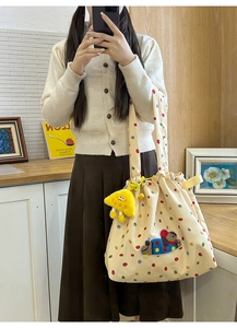 Detail of beige canvas tote bag featuring colorful polka dots and cute dog plush applique