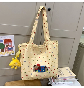 Detail of canvas tote bag featuring colorful polka dots and cute plush dog patch applique