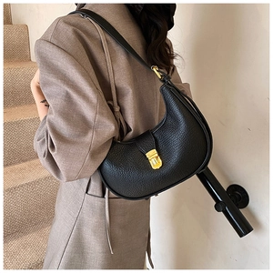 Close-up of black lychee grain leather crescent bag with gold clasp on a model