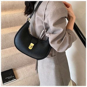 Detail of black pebbled leather croissant bag with metallic gold buckle and texture