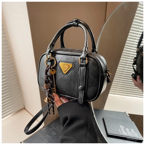 Detail der schwarzen Boston-Tasche mit goldenem Dreieckslogo und Schlüsselanhänger