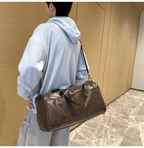 Detail of a large brown faux leather travel bag with shoulder strap and side logo