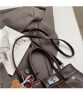 Detail of dark brown handbag with contrast white stitching and silver twist lock closure