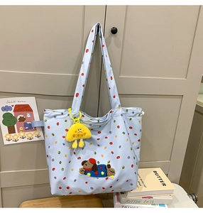 Detail of light blue polka dot tote bag with cute dog embroidery and yellow charm