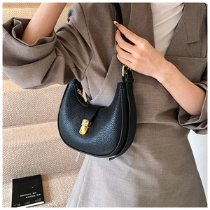 Detailed view of a black pebbled leather half-moon bag on model with gold hardware detail