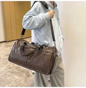 Detail of large brown leather travel bag with shoulder strap and side shoe compartment