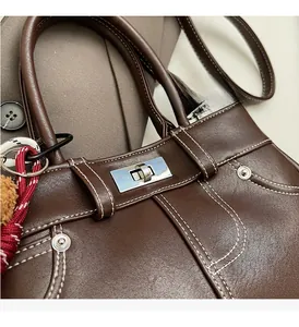Close-up of retro dark brown leather handbag featuring silver twist lock and contrast stitching