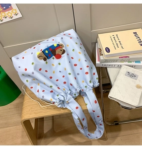 Detail of light blue polka dot tote bag featuring a cute plush bear embroidery patch