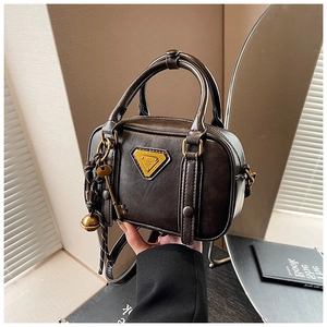 Detailansicht der braunen Vintage-Kunstledertasche mit Metallschlüssel- und Glockenanhänger