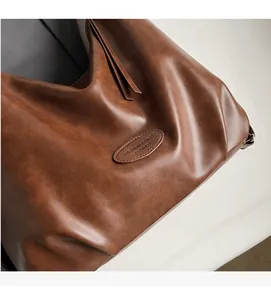 Dettaglio della borsa vintage in pelle marrone con trama morbida e cerniera con nappa