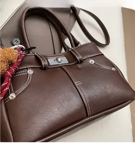Detail of lychee pattern leather handbag with white stitching and silver turn-lock