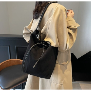 Minimalist black bucket shoulder bag with decorative bow detail and long strap